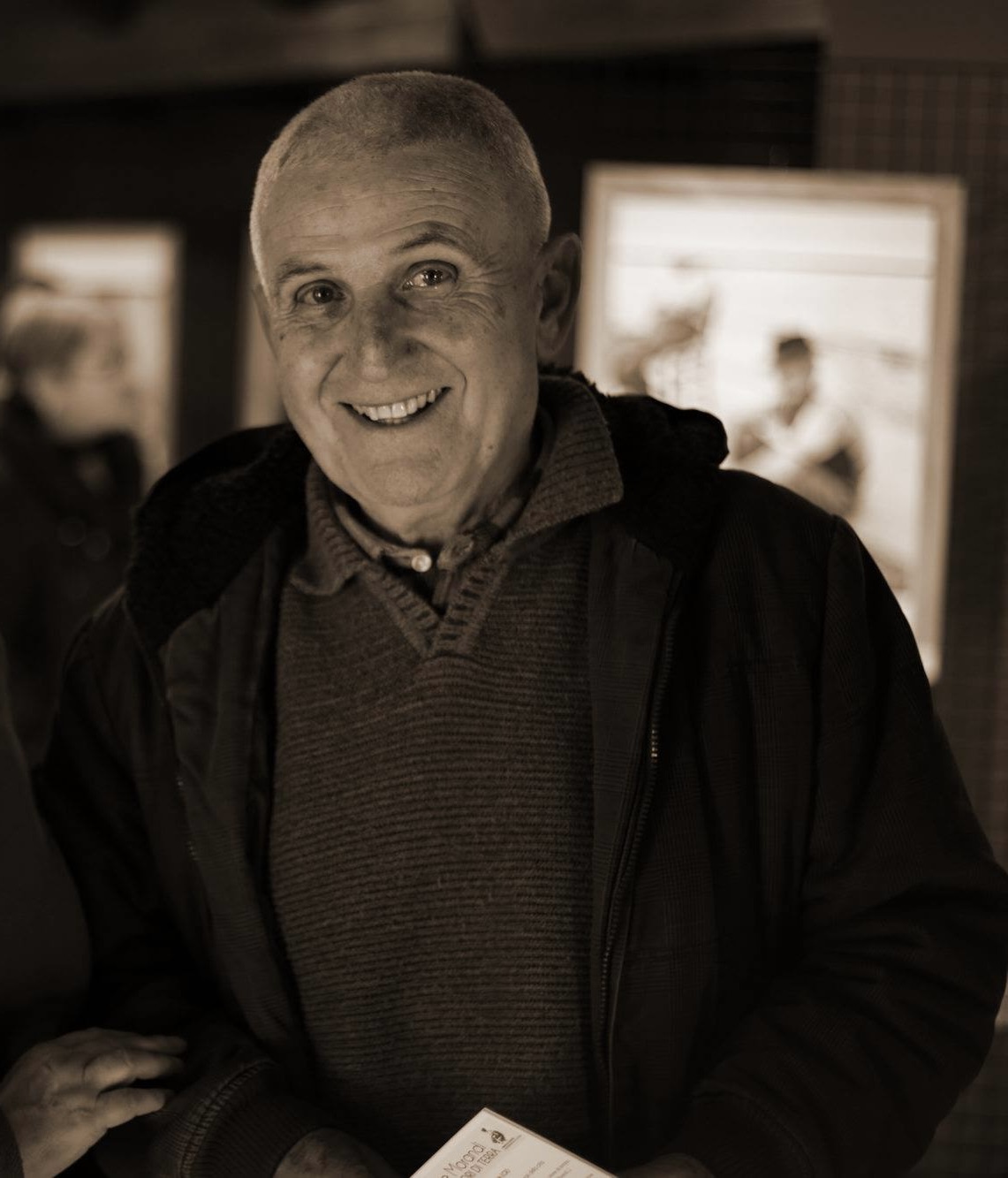 Una fotografia in toni seppia, in formato verticale, che ritrae Giuseppe Morandi da davanti, coi capelli bianchi corti, sorridente.