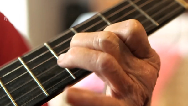 La mano sinistra di Giovanna Marini prende un accordo sulla sua chitarra