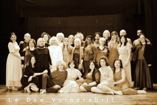 Una foto che ritrae il gruppo de "Le dee vulnerabili" in posa su un palco, tutte a piedi nudi, sorridenti e belle