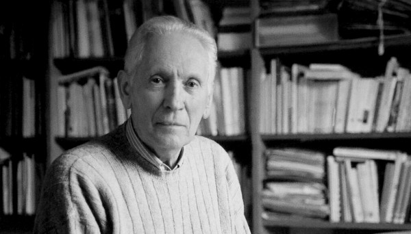 Ritratto fotografico di Mario Lodi di fronte a una libreria piena di libri